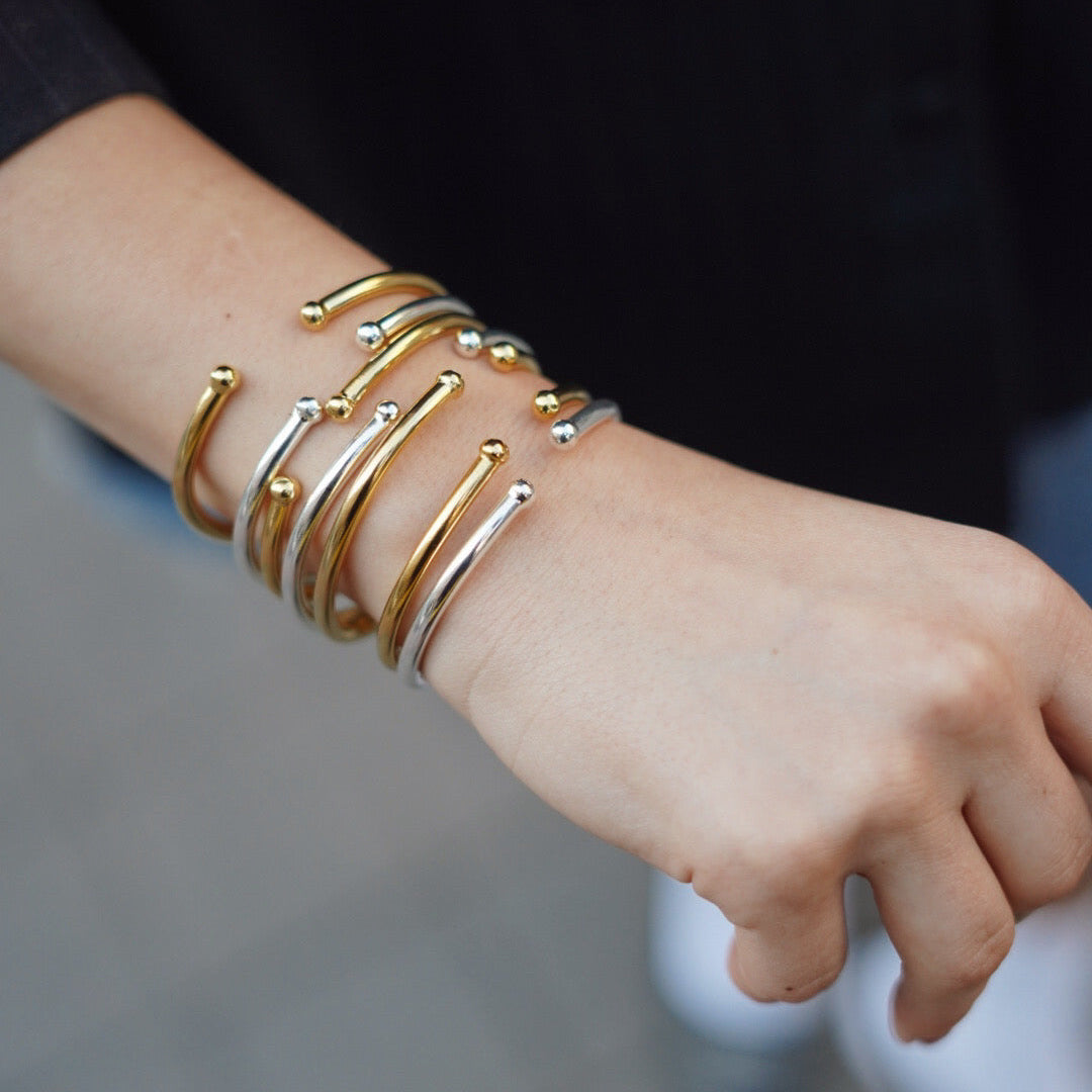 Combinación de pulseras rígidas apilables en oro y plata de nuestra colección de brazaletes para mujer.